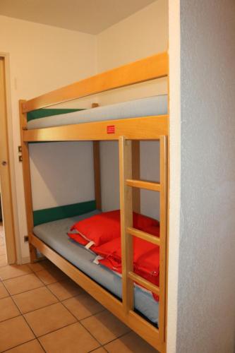 Ce lit superposé se trouve dans un dortoir doté de draps rouges. dans l'établissement Appartement au départ des remontées mécaniques - Briançon, à Briançon