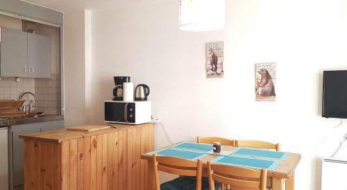 kuchnia ze stołem, krzesłami i kuchenką mikrofalową w obiekcie Appartement au départ des remontées mécaniques - Briançon w mieście Briançon