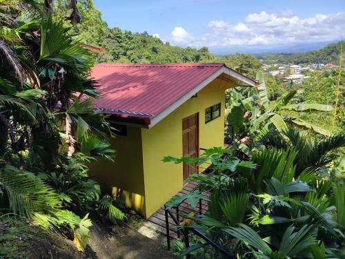 a yellow house with a red roof in the jungle at Villas In Sueño Private Jungle Hotel in Manuel Antonio