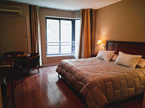 1 dormitorio con cama y ventana grande en Estudio / monoambiente ubicación privilegiada en Mendoza