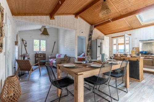 Il dispose d'une cuisine et d'un salon avec une table et des chaises en bois. dans l'établissement Capfun 5 stars 64 m with pool and terrace, à Lanton