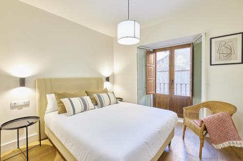 - une chambre avec un grand lit blanc et une fenêtre dans l'établissement Estudios Bordadores by Valdesierra, à Salamanque