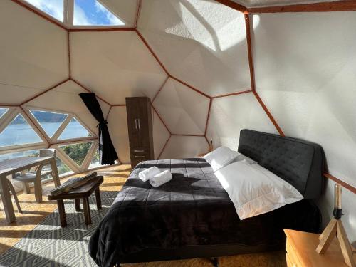 1 dormitorio con 1 cama en una habitación con ventanas en Glamping Vista Lago Guatavita, en Guatavita