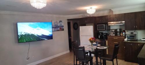 a kitchen with a table and a television on a wall at Oscar INN & 2bd Family Suite or Private Room in Abbotsford