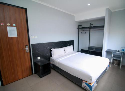 um quarto com uma cama branca e uma porta de madeira em Bale Resident em Jakarta