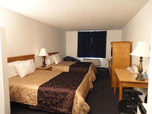 a hotel room with two beds and a desk at South Hill Motor Inn in Red Deer