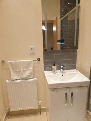 a bathroom with a sink and a mirror at London Luxury Apartment 3 Bed 1 minute walk from Redbridge Stn Free Parking in Wanstead