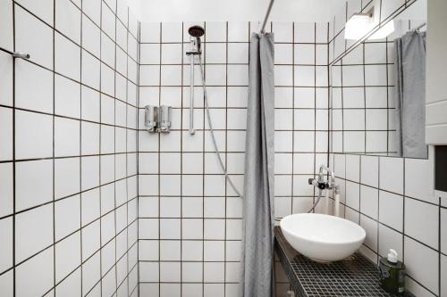 a white tiled bathroom with a sink and a shower at Randers residence Sankt Andreas - 2 room apartment in Randers