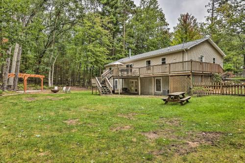 una casa grande con un patio con parque infantil en Charming Pentwater Home with Fire Pit and Yard!, en Pentwater