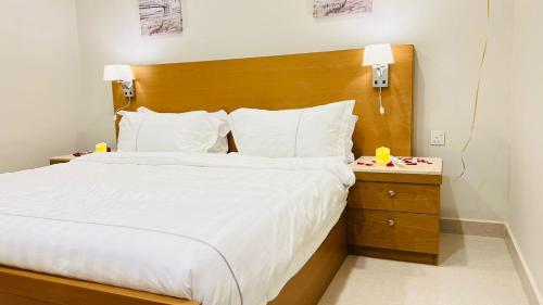 アル・カルジにあるAljadel hotelのベッドルーム1室(大型ベッド1台、木製ヘッドボード付)