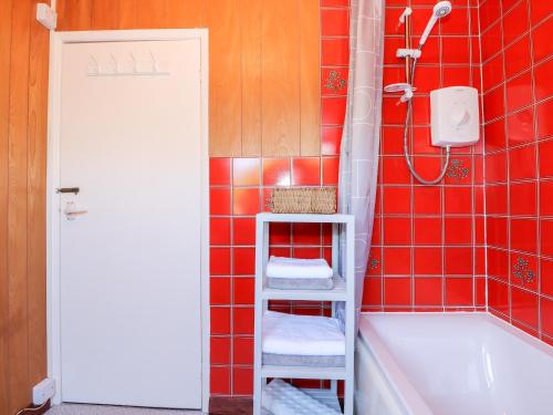 a red tiled bathroom with a shower and a bath tub at Meadowsweet in Skegness