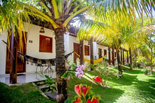 una casa con una palmera en el patio en Recanto Caiçara Pousada, en São Miguel dos Milagres