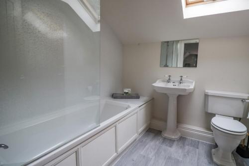 a bathroom with a tub and a sink and a toilet at The Annexe, Melbourne House in Penrith
