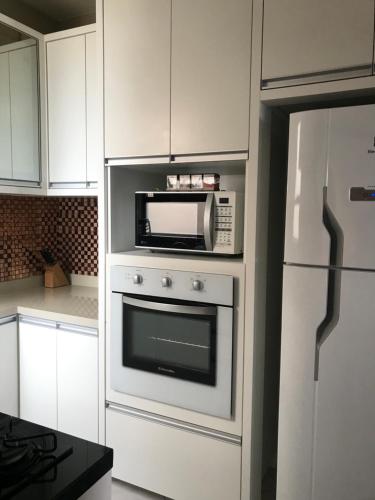una cucina bianca con forno a microonde e frigorifero di Lindo apartamento com vista para o mar a Matinhos