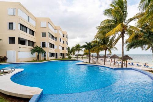 a large swimming pool next to a building and the beach at Departamento frente al Mar - Kiara in Cancún