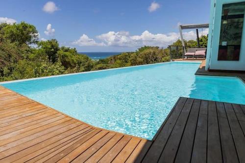 - une piscine avec une terrasse en bois et l'océan dans l'établissement STUDIO O'KALM, au Gosier