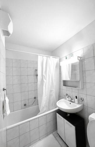 a white bathroom with a sink and a bath tub at Eine schöne Wohnung im Herzen von Basel. in Basel