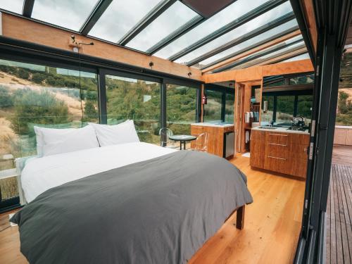 a bedroom in a glass house with a bed and a sink at Manakau PurePod in Kaikoura