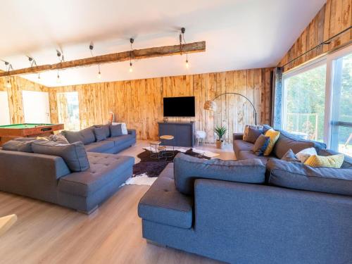 a living room with blue couches and a tv at Lush chalet near lake of B tgenbach in Wirtzfeld