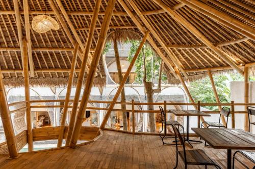 a restaurant with a straw roof with tables and chairs at Clan Living - The Founder Ubud in Ubud