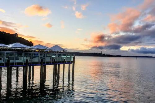 a resort on the water at sunset at Garden Bliss & Bird Sanctuary in Paihia Estuary in Paihia