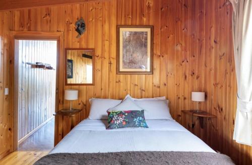 ein Schlafzimmer mit einem Bett in einer Holzwand in der Unterkunft The Boomerangs at Johanna on the Great Ocean Road in Johanna