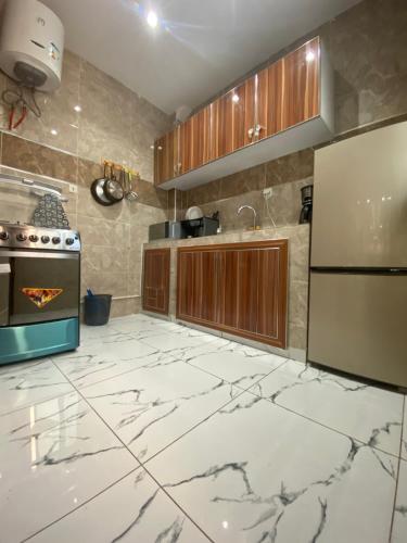 uma cozinha com piso em mármore branco e armários de madeira em Chez El Hadji et Hamidou em Dakar