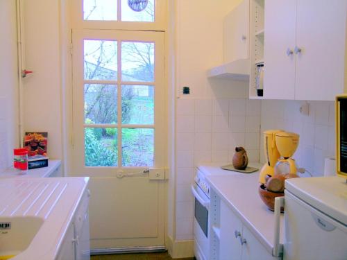 a kitchen with white cabinets and a window at Maison confortable près de village médiéval avec jardin clos - FR-1-489-15 in Hérisson