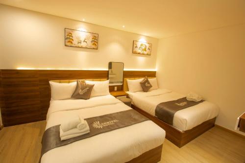 a hotel room with two beds and a tv at Carnival Hotel - Đà Lạt in Da Lat