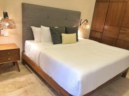ein Schlafzimmer mit einem großen weißen Bett und einem Nachttisch in der Unterkunft 206 Amena Boho Modern Oasis Best Location&Fast WIFI in Tulum