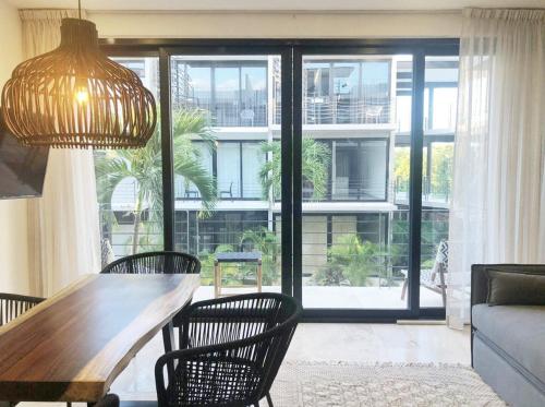ein Wohnzimmer mit einem Tisch und Stühlen sowie einem großen Fenster in der Unterkunft 206 Amena Boho Modern Oasis Best Location&Fast WIFI in Tulum
