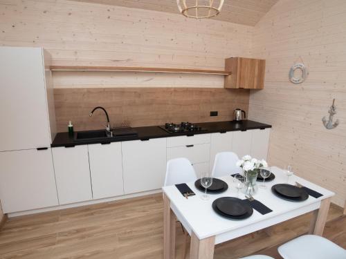 a kitchen with white cabinets and a white table and chairs at Cottages close to the sea, Wicie near Jaros awiec in Wicie