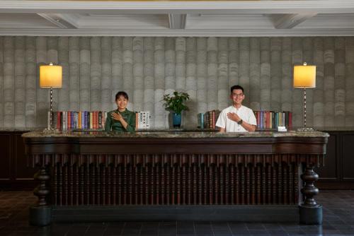 2 personnes debout derrière un bar dans une pièce dans l'établissement La Siesta Hoi An Resort & Spa, à Hội An