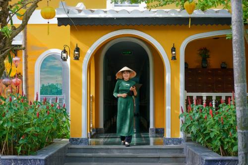 a woman standing in the doorway of a yellow house at La Siesta Hoi An Resort & Spa in Hoi An