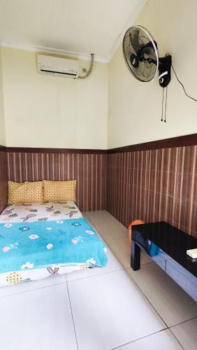 a bedroom with a bed and a fan and a table at Homey Guesthouse near Sby Zoo Syariah in Surabaya