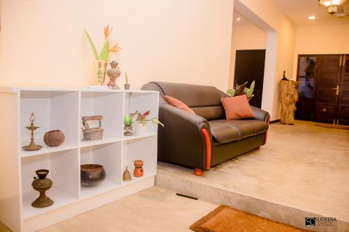 a living room with a brown couch and shelves at Blooming polhena in Matara