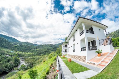 a white house on a hill overlooking a river at Hotel Campestre El Triunfo in San Agustín