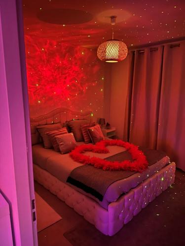 um quarto com uma cama grande com flores vermelhas em Jacuzzi Appartement love room em Freneuse