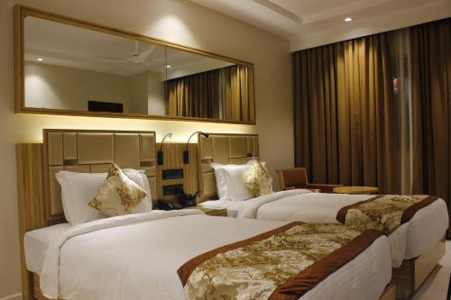 a hotel room with two beds and a mirror at Mango Hotels Vijayawada in Vijayawāda