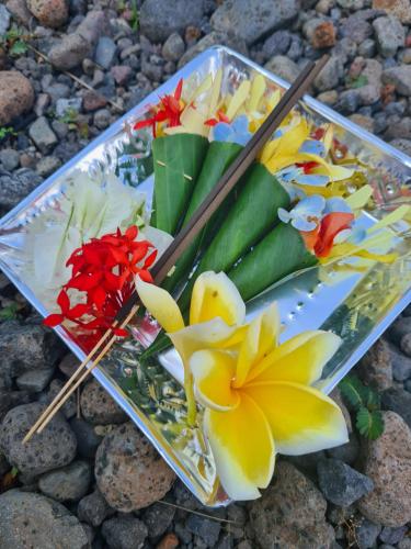 a tray with flowers and chopsticks on top of rocks at Guest house KupuKupu39 in Kuta
