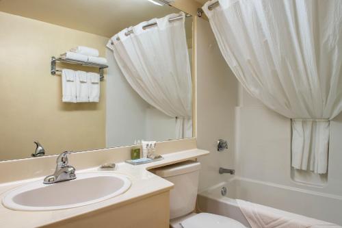 a bathroom with a sink and a toilet and a mirror at Travelodge Suites by Wyndham Regina - Eastgate Bay in Regina