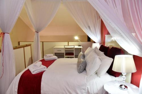 a bedroom with a large white bed with curtains at Villa Moria Romance in Dullstroom