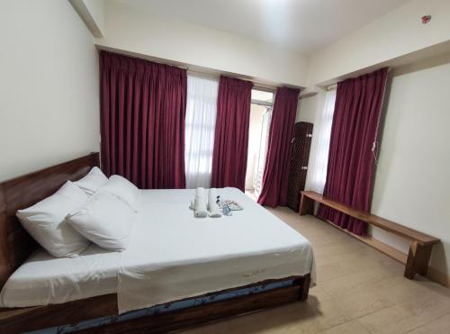 um quarto com uma cama branca e cortinas vermelhas em Twinlakes Condominium Tagaytay, LL1R Shiraz em Tagaytay