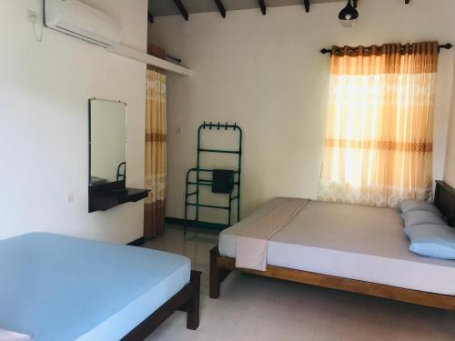 a bedroom with two beds and a window at Hotel Ganthera Kataragama in Kataragama