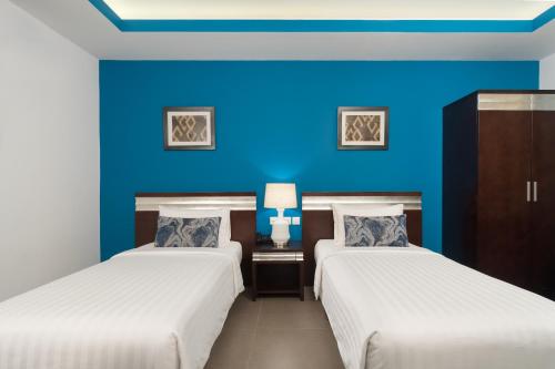2 camas en una habitación con una pared azul en Al Hail Waves Hotel Managed By Centara en Seeb