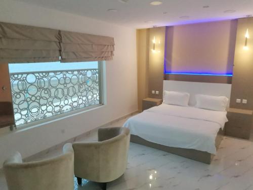 a bedroom with a bed and two chairs and a window at Marina H in Sohar