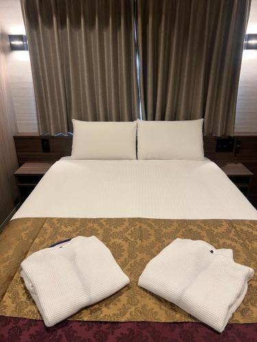 a bed with two white towels on top of it at HOTEL GrayⅡ in Osaka