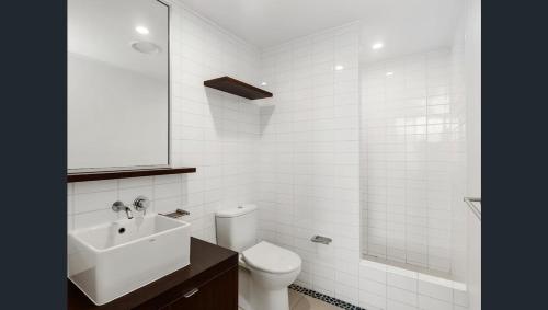 Baño blanco con aseo y lavamanos en 3 Bedroom Central Beachside Kingscliff Apartment with Pool, en Kingscliff