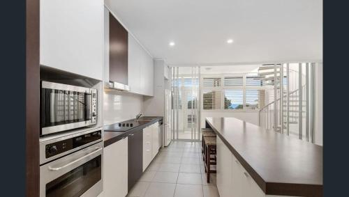 a kitchen with white cabinets and a counter top at 3 Bedroom Central Beachside Kingscliff Apartment with Pool in Kingscliff