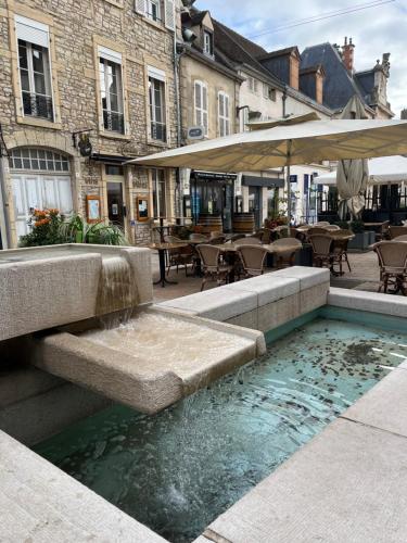 a fountain in a courtyard with tables and chairs at Le cocoon Nuits in Nuits-Saint-Georges